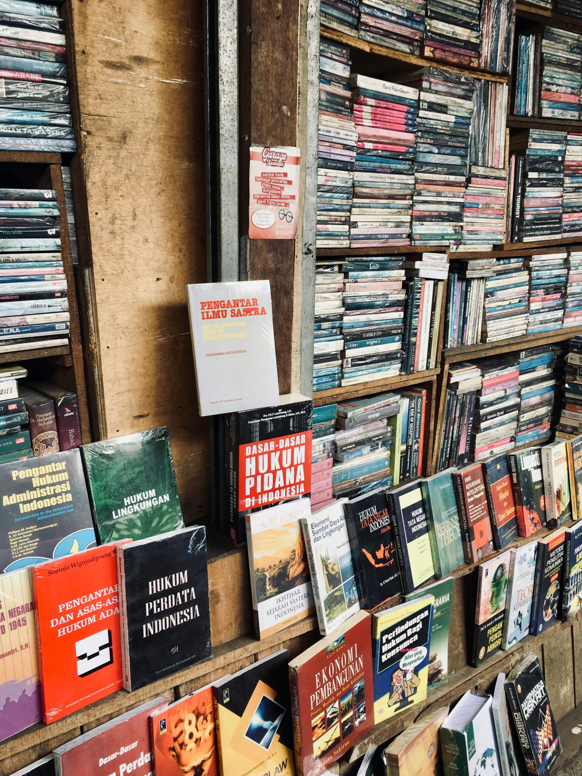 Explore a variety of books on wooden shelves in an Indonesian bookstore.